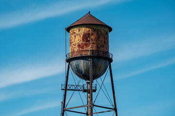 A rusty water tower against a blue sky