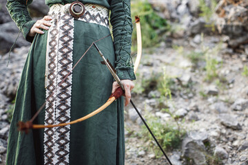 Beautiful red-haired girl-archer of Middle Ages among rocks. Fantastic concept