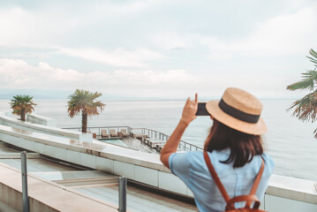 Fototapeta na wymiar woman traveler taking picture on her phone sea beach