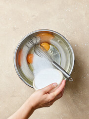 sugar is added to the eggs in a metal bowl
