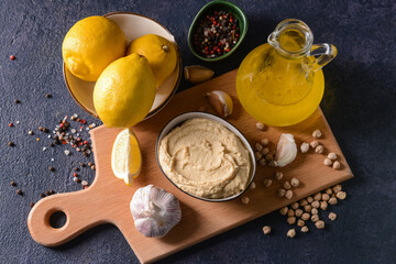 Composition with tasty hummus and ingredients on dark background