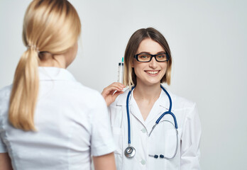 female doctor syringe in hand treatment light background