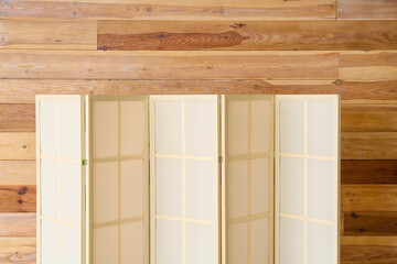 Stylish folding screen near wooden wall