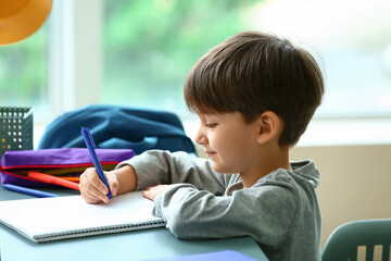 Little boy writing in notebook at home