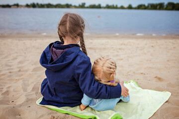 Lonely adorable eight years girl playing with doll on the autumn beach, mother and daughter game,...