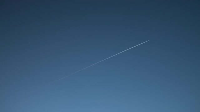 4K Video clip of jet airplane airliner flying leaving vapour trail across a cloudless blue sky