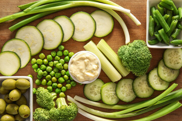 Board with different green vegetables on color background