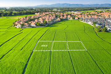 Land for sale and investment in aerial view. Include green field, agriculture farm, residential house building, village. That real estate or property. Plot of land lot for subdivision or development.