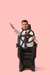 Obraz premium Angry businessman in car seat and with steering wheel on color background