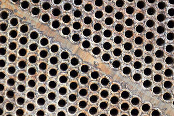 Tube sheet plate of heat exchanger or boiler closeup texture macro diagonal background with insoluble hard mineral deposits salts scale and corrosion. Trypophobia concept.