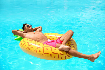 Handsome man with inflatable ring in swimming pool