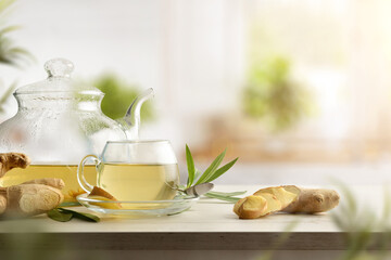 Cup with ginger drink on bench with teapot in kitchen