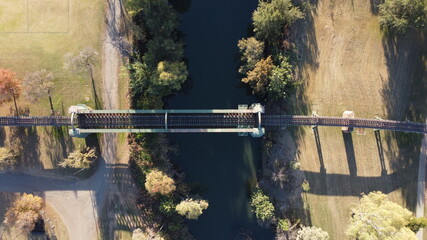 Old steel train bridge viaduct crossing a autumn tree lined small river and fields in regional Australia