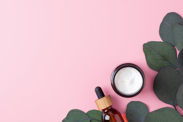 Cosmetic skin care products with eucalyptus on pink background. Flat lay, copy space