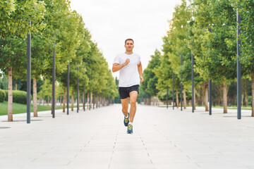 Fototapeta premium Young sports athlete man in white t-shirt run in the morning in modern park.