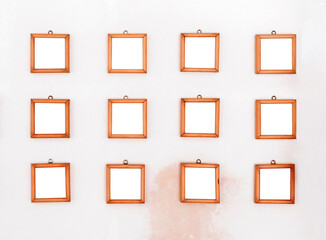 Twelve small simple square wooden frames displayed on a wall