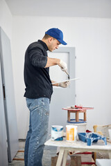 Young adult man painting on a DIY budget renovation of his new home apartment.