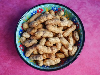 Photo of a ceramic bowl full of peanuts in shell. Healthy vegan snack or food concept.