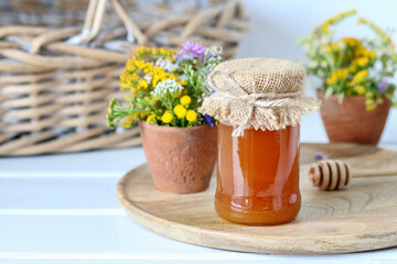 Jars with honey and bouquet of wild flowers on the table.