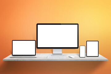 Responsive display devices mockup on desk. Computer display, laptop, tablet and phone with isolated screen. Orange wall in background
