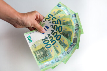 Male hand holds European money Euro on white background: 100 euro currency banknotes. Inflation, business, economics and finance theme. - obrazy, fototapety, plakaty