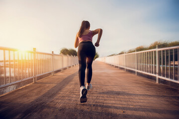 young fitness woman runner athlete running on the road at sunset.