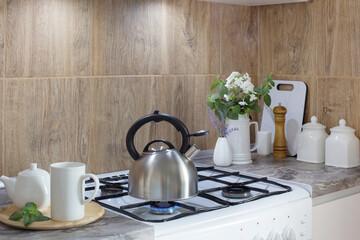metal silver kettle on   gas stove  and teapotwith cup  in kitchen