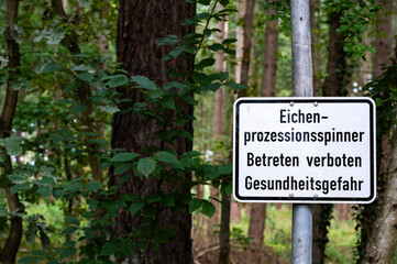 Ein Schild warnt vor dem gefährlichen Eichenprozessionsspinner am Waldrand