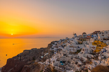 Sunset view of the cliff side white cave accommodation of Oia on the Greek island of Santorini
