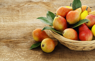 fresh pears with leaves in a basket on wooden background