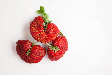 Ripe funny strawberry berries. Trendy food. Concept - Eating ugly fruits and vegetables. Top view,...