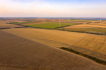 Many agriculture fields and wind turbines on a sunny day. Drone photo