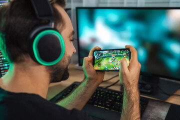 Young man gamer playing video games on smartphone