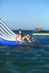 Caucasian boy of nine year old having fun at the inflatable beach aqua slide
