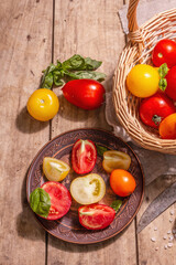Ripe assorted tomatoes with fresh basil in a wicker basket