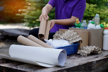Concept : categorize type of garbage. Housekeeper is separating recyclable rubbish ; paper, plastic, egg cartons before throwing away or selling to local recycle factory.             