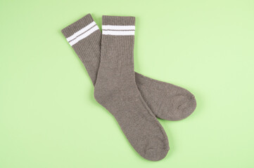 Pair of gray socks with white strips on light green pastel background, top view