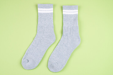 Pair of gray socks with white strips on light green pastel background, top view