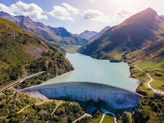 Water dam and reservoir lake in Swiss Alps generating hydroelectricity. Aerial view of arch dam...