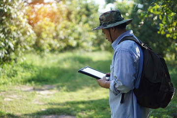 Asian male backpack hiker travel alone in forest , survey and collect information of botanical...