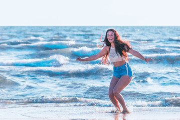 Young woman playing in the sea.woman make in sea water splash.Cheerful young woman having fun on the summer beach.