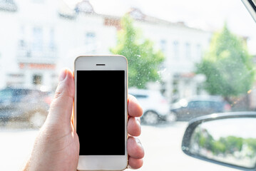 Man using phone in car, GPS navigation ,blank space frame on smartphone in hand with blur image of traffic.