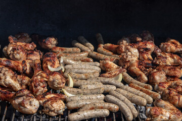 Closeup of chicken meat and sausages with onions over the coals on a barbecue. Concept food. BBQ.
