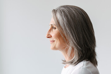 Grey senior woman in t-shirt Grey senior woman in t-shirt smiling while posing in profile aside...