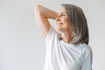 Grey senior woman in t-shirt smiling and looking aside