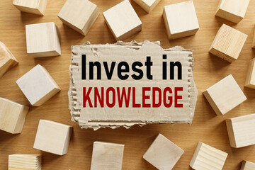 Invest In Knowledge. text on torn cardboard on wood cubes background