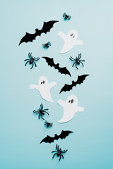 Halloween flat lay composition with ghosts, spiders, bats on blue background. Flat lay, top view, overhead.