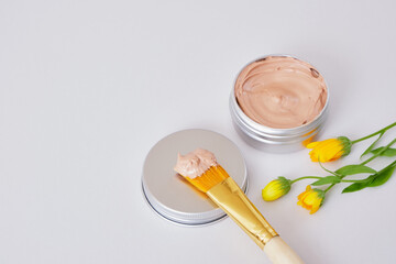 small beautiful flowers, makeup brush and cosmetic red clay in an aluminum jar, natural cosmetics