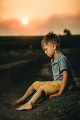 Fototapeta na wymiar little boy sitting at sunset and crying