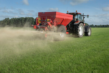 Fertilizer spreader. Fertilizer. Tractor. Farming. Meadow. Grass. Chalk. Netherlands